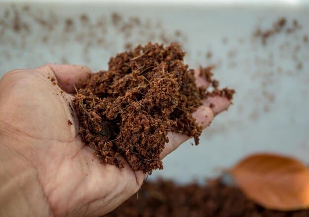 Close-up of richly textured, dark brown finished compost being held in a gardener's gloved hand, showing its crumbly consistency, ready for use in a garden.